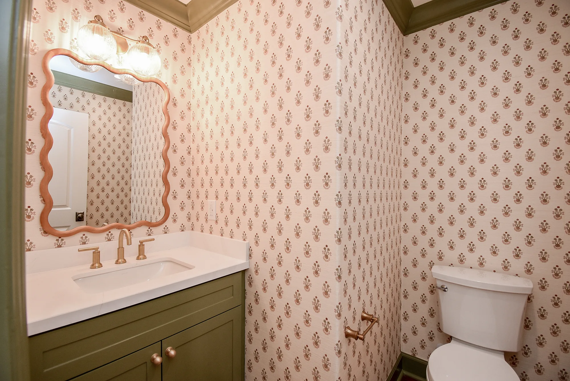 Remodeled Grovewood guest bathroom with patterned wallpaper and green vanity